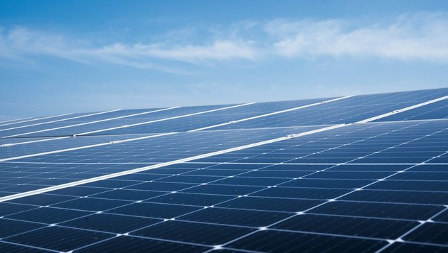 Rows of solar panels installed on a rooftop under a blue sky