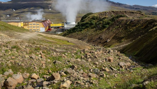 A geothermal power plant with steam rising in a mountainous landscape