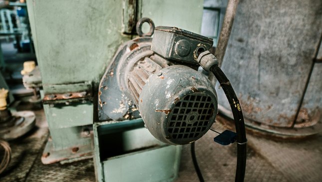 An old electric motor attached to industrial equipment